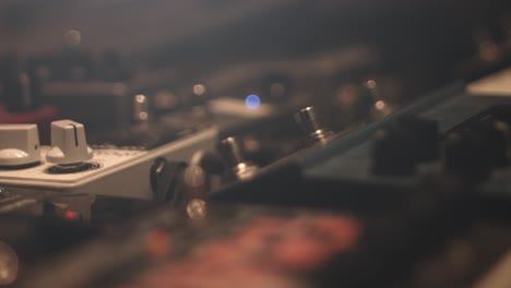 Close-up-of-different-guitar-pedal-effect-stomp-boxes-on-the-floor-in-a-recording-studio-with-knobs-and-led-indicator-lights