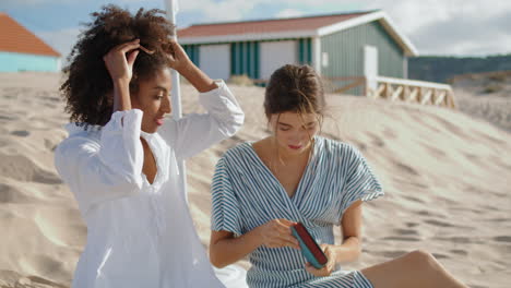 Two-women-holding-book-resting-beach-picnic.-Beautiful-multiethnic-lgbt-couple