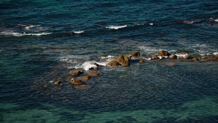 Le onde si infrangono contro formazioni rocciose lungo la costa turchese di Tangeri, Marocco.