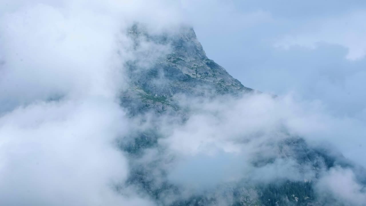 Timelapse di nuvole che coprono la cima blu di una montagna con una torre in cima