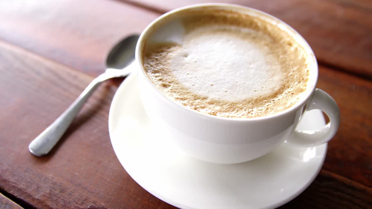 Cup of coffee with saucer and spoon on table