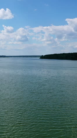 evening water under blue sky. beautiful wide river landscape. calm river among fields and forests. aerial flight. vertical video