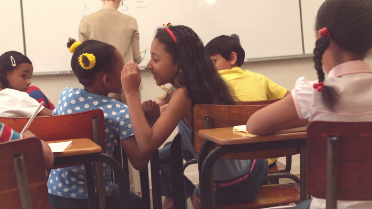 alumnos susurrando secretos durante la clase