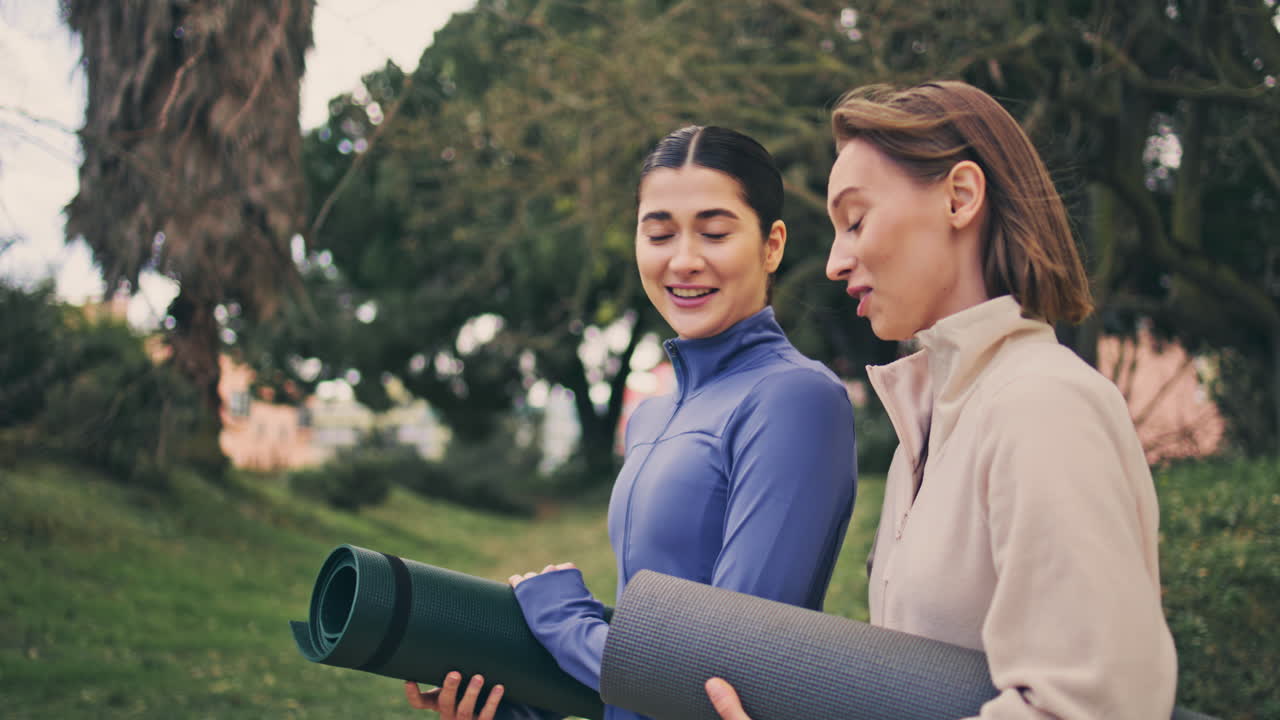 mujeres deportivas felices en el parque hablando de cerca. mujeres riendo caminando juntas.
