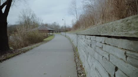 stone wall leading to a strolling road next to a frozen lake in winter