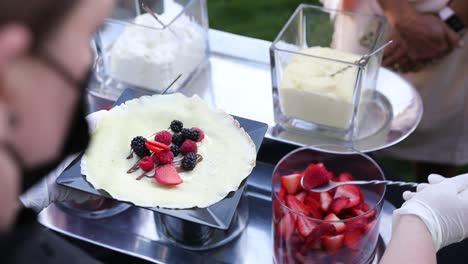 preparation of crepe with strawberries and berries served elegantly