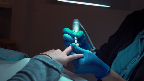 Woman-in-a-nail-saloon,-Manicurist-prepares-nails-for-paint-with-electric-file-drill