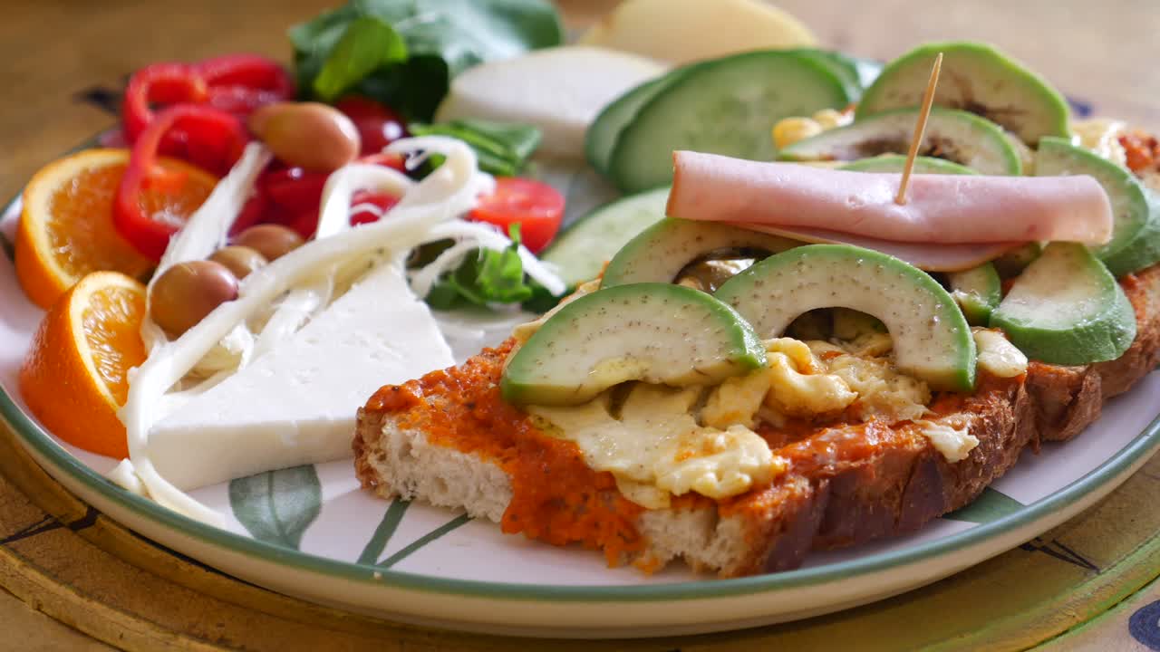 A colorful and healthy breakfast platter with sandwich, cheese, fruits and vegetables
