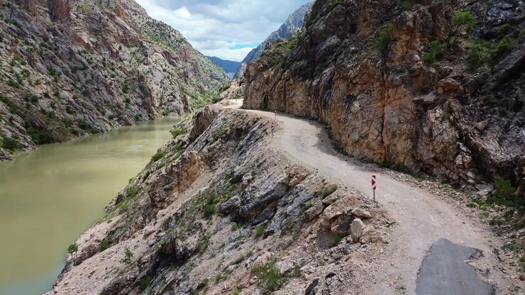 Volo panoramico con drone all'interno della profonda gola del Canyon di Karanlik che mostra lo stretto sentiero stradale in pietra scolpito a mano su un fianco della scogliera. Maestoso terreno montuoso e natura selvaggia in Turchia