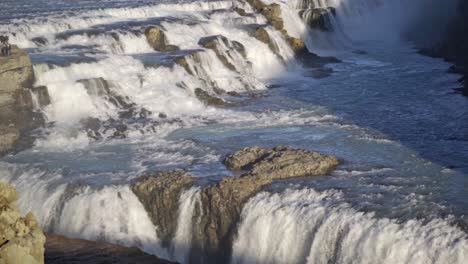a breathtaking close-up of gullfoss waterfall at sunset, showcasing its powerful, multi-tiered cascades illuminated by the warm, golden light against a rugged icelandic landscape