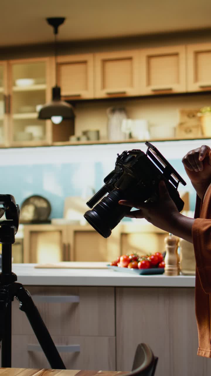 Video verticale: influencer afroamericano sistema l'attrezzatura fotografica dietro le quinte.
