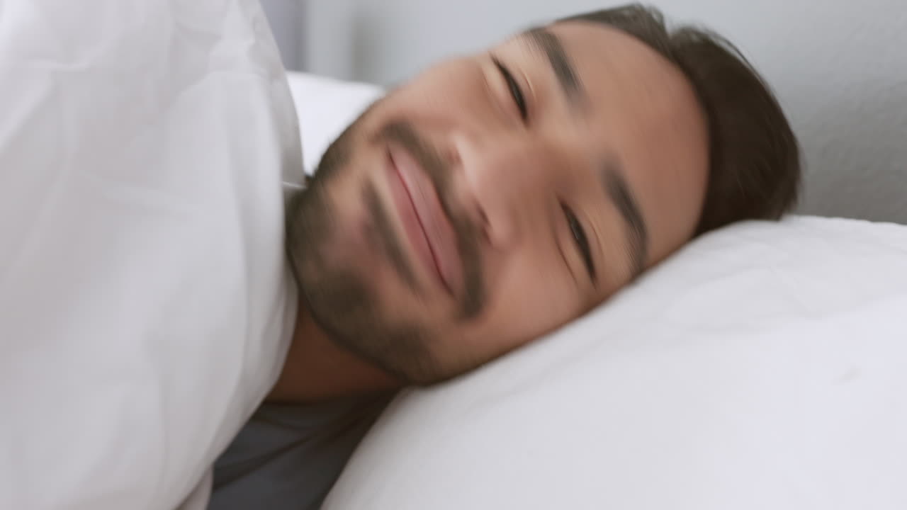hombre feliz despierta en la cama y sonríe por la mañana