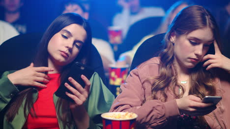 Upset-women-checking-mobile-phone-in-cinema