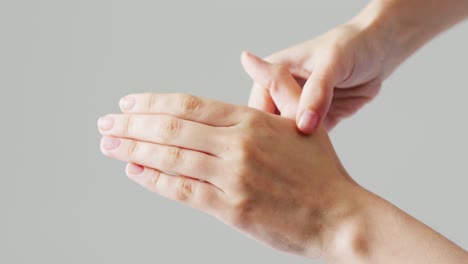 video detail of caucasian woman massaging hand with fingers and thumb, with grey copy space