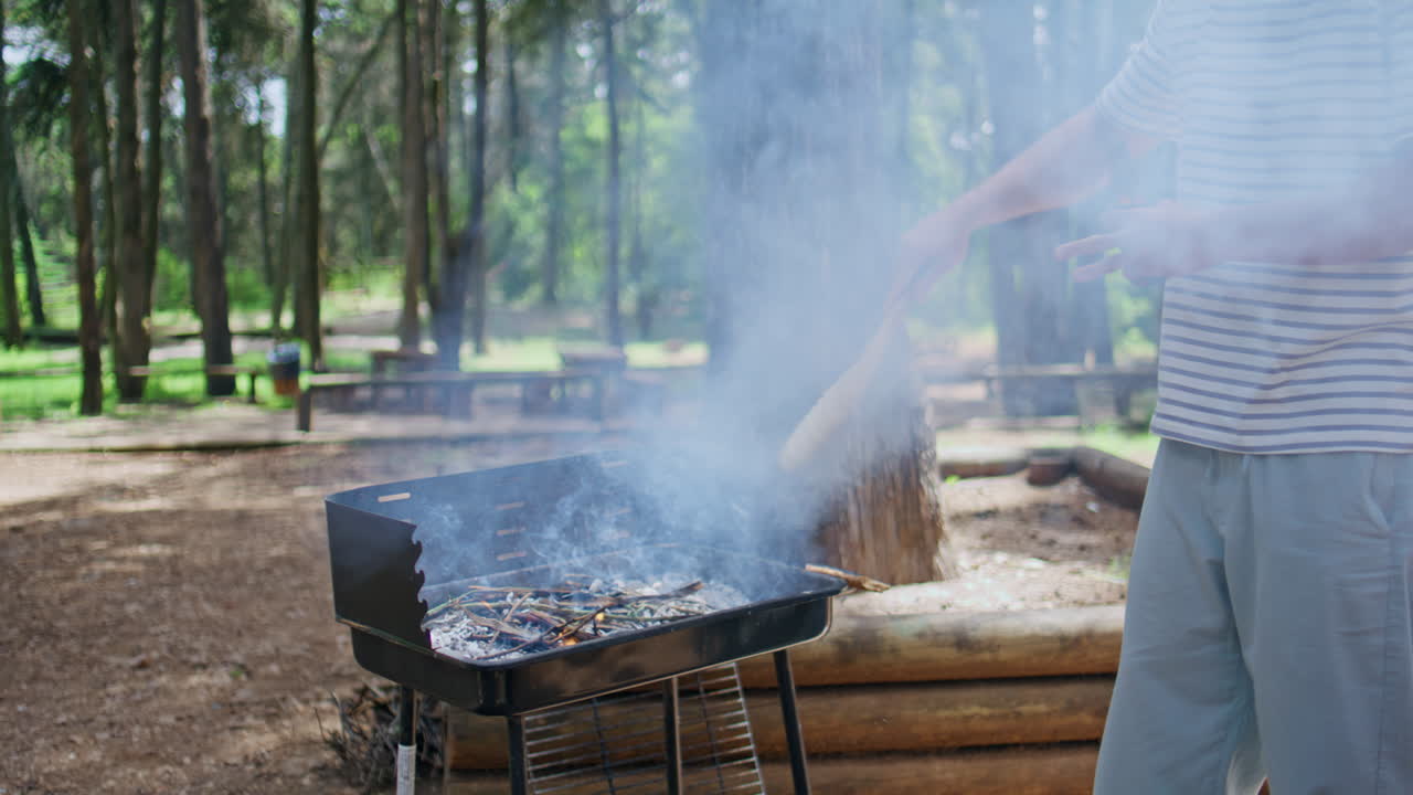 Man cooking grill park surrounded by smoke and nature. Unknown guy preparing