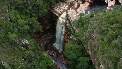 Aerial-drone-rising-tilt-down-shot-of-the-incredible-Mosquito-Falls-surrounded-by-tropical-jungle-and-cliffs-in-the-Chapada-Diamantina-National-Park-in-Northeastern-Brazil-on-a-warm-sunny-summer-day