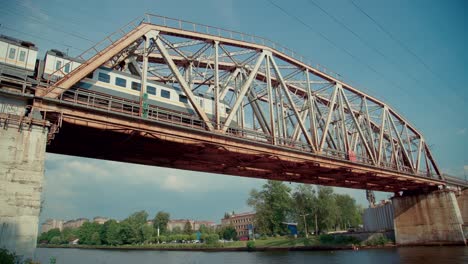 moving train on the railway bridge over the river. modern public transport architecture.