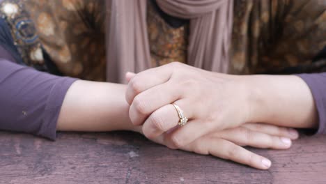 manos de la mujer con anillo en la mesa de madera