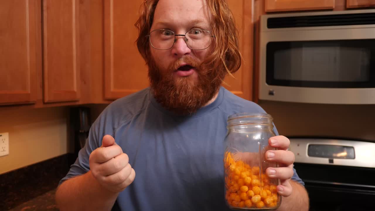 Red haired male rushing to eat protein chips puffs.