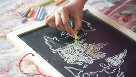 child drawing a world map on a blackboard