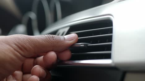 close-up of a hand adjusting the air vent in a car