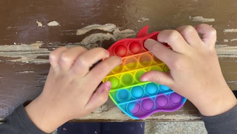 girl's-hands-playing-with-apple-shaped-pop-it