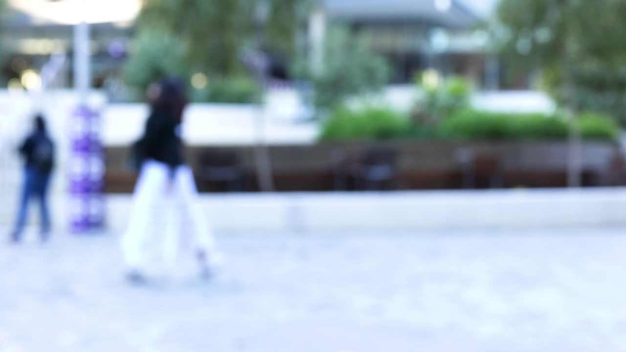 Blurry figures walking in a public square