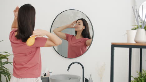 woman brushing her hair in front of a mirror in the bathroom