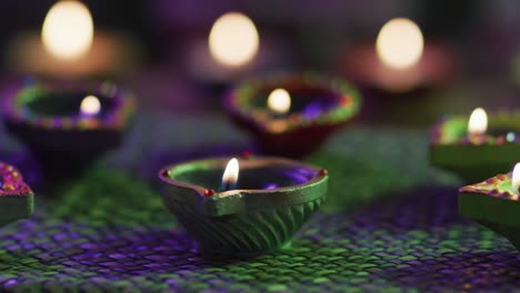 velas encendidas en ollas de arcilla decorativas en alfombra de mesa tejida, enfoque en primer plano, fondo bokeh