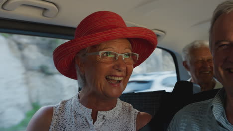 group of senior friends sitting in back of people carrier being driven to vacation