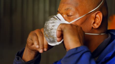 worker removing mask in foundry workshop 4k