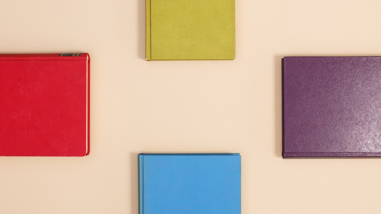 cuatro libros antiguos de tapa dura en cuatro lados aparecen sobre un fondo beige.