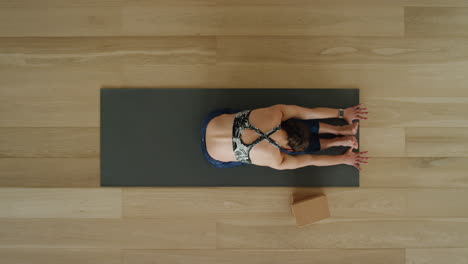 Die-Oben-Gezeigte-Yoga-Frau-übt-Die-Vorwärtsbeuge-Pose-Im-Sitzen-Im-Trainingsstudio-Und-Genießt-Einen-Gesunden-Lebensstil,-übt-Meditationsübungen-Auf-Einer-Trainingsmatte