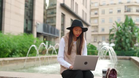 hispanic woman browsing laptop on street