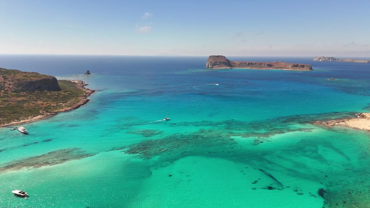 La Laguna di Balos e l'Isola di Imeri Gramvousa presentano acque turchesi poco profonde, sedimenti sabbiosi e fondale marino roccioso vicino a Kissamos, Chania, Creta, Grecia, durante un sorvolo in avanti con drone