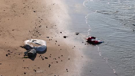 waves approach trash on sandy beach