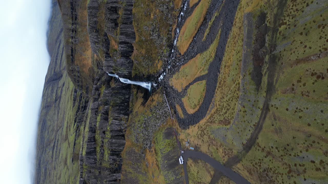 척박한 아이슬란드 풍경에 있는 폭포의 수직 항공 영상