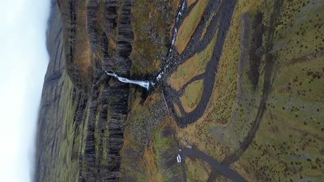 vertical aerial video of waterfall in barren icelandic landscape