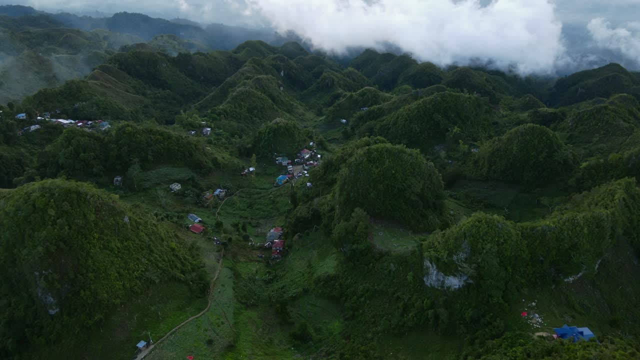 pico de osmena, filipinas con colinas verdes y una pequeña aldea en medio de nubes al anochecer, vista aérea