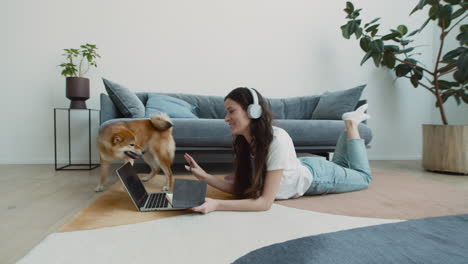 lindo perro lame la cara de su dueña mientras ella tiene una videollamada de trabajo en su computadora portátil