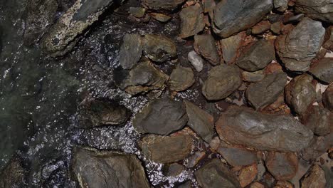 vertical-drone-tracking-shot-of-granite-rocks-and-small-ocean-waves