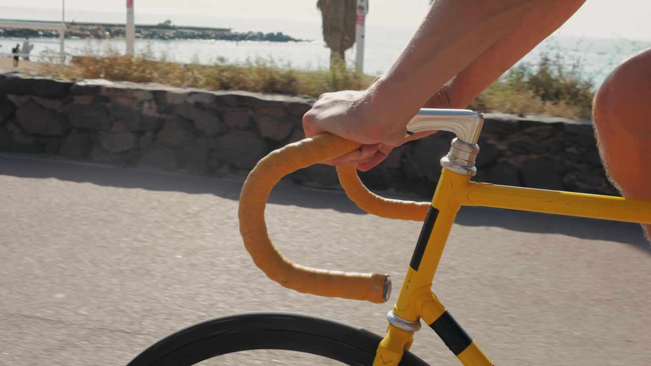 Person riding a yellow fixed gear bicycle on a coastal path