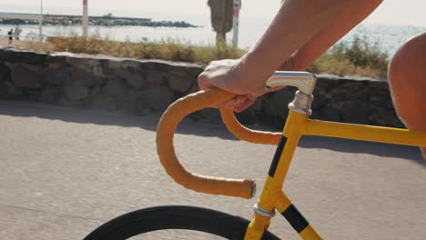person riding a yellow fixed gear bicycle on a coastal path