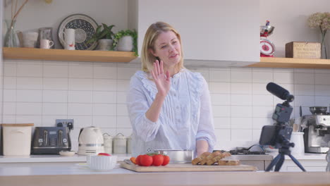Woman-vlogging-making-social-media-video-about-food-at-home-in-kitchen-on-mobile-phone---shot-in-slow-motion