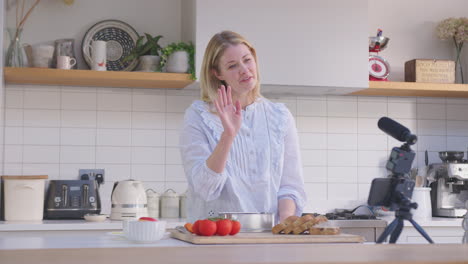 mujer vlogging haciendo video de redes sociales sobre la comida en casa en la cocina en el teléfono móvil - filmado en cámara lenta