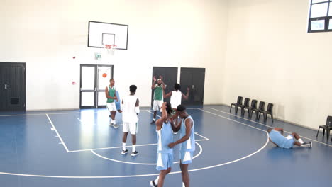multiracial male basketball players playing basketball, passing and throwing basketball in gym