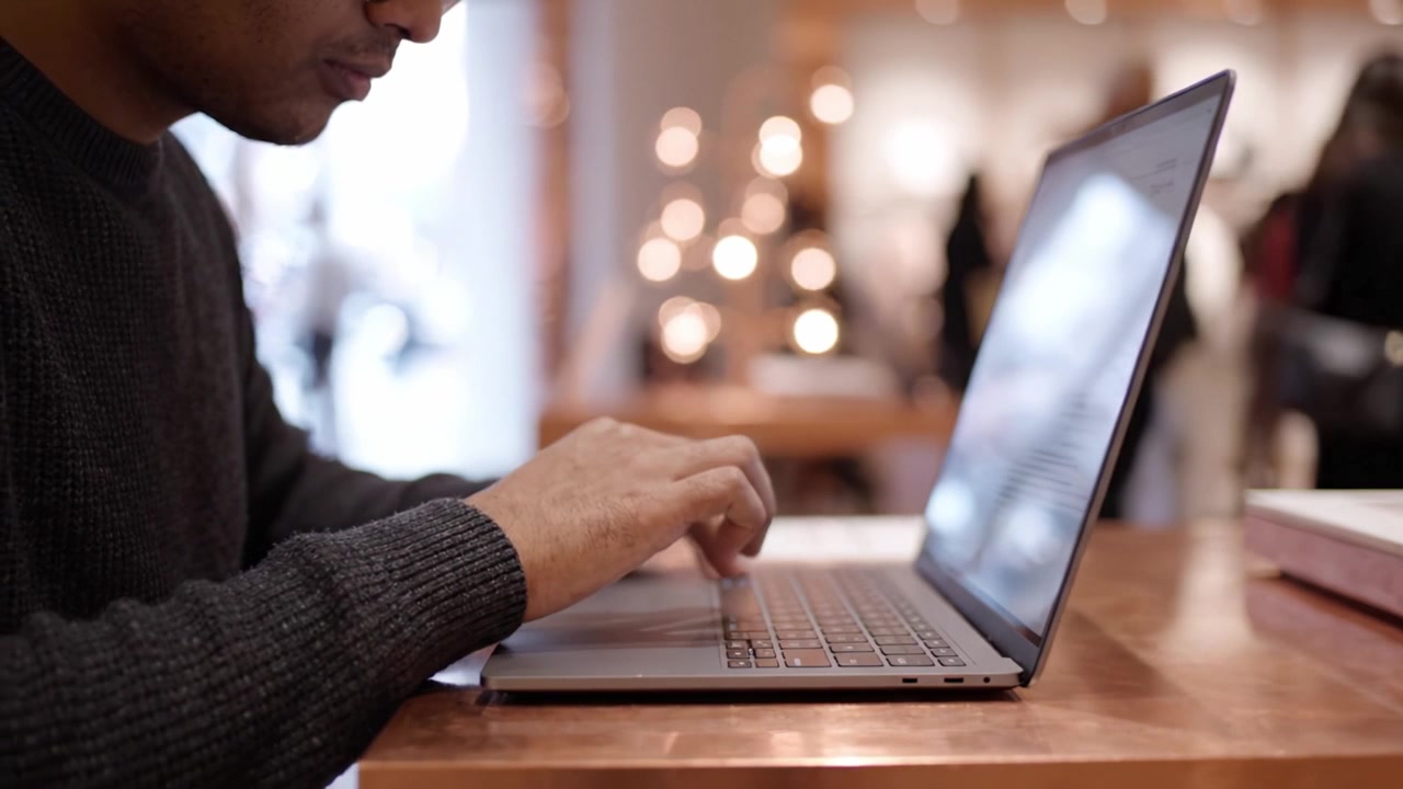 A Close-Up of a Person Working on a Laptop in a Modern Environment with Soft Lighting and a Contemporary Design Theme Reflecting Focus and Productivity