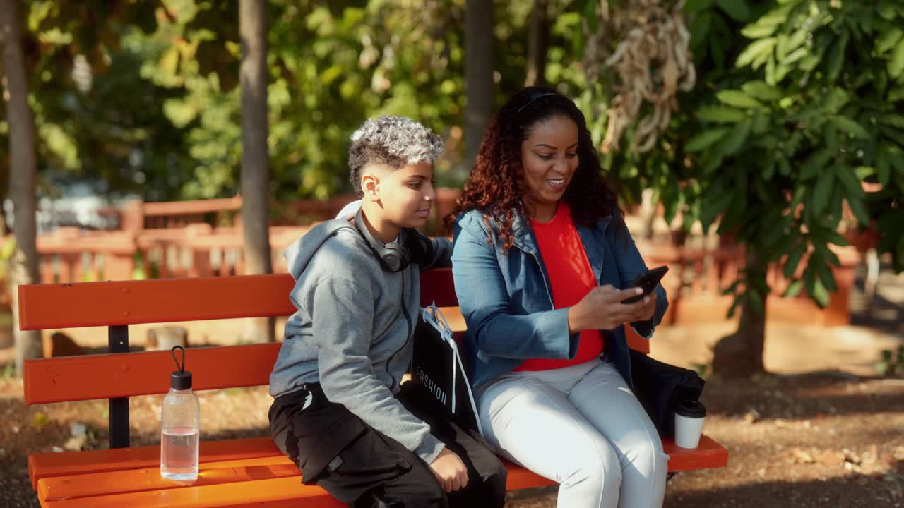 Mother and Son Sharing a Mobile Phone Moment on a Park Bench