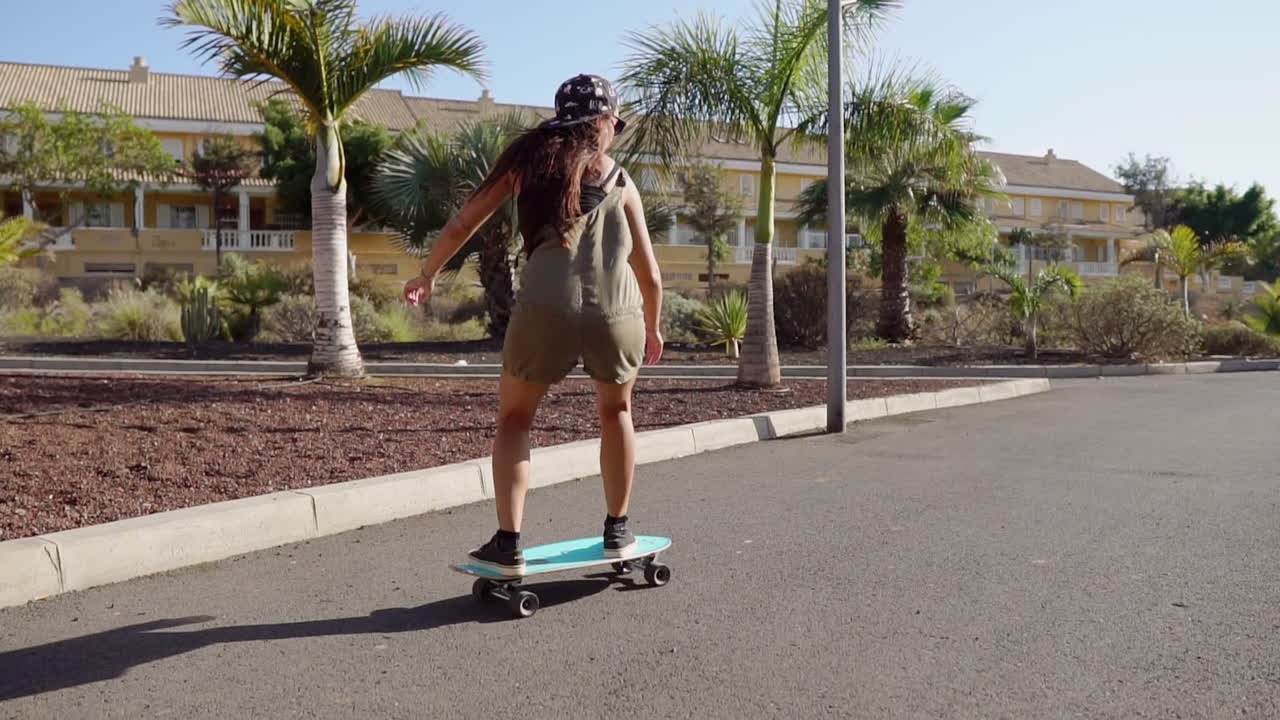 In slow motion, a girl's longboard journey by the beach and palm trees unfolds, showcasing both beauty and skill