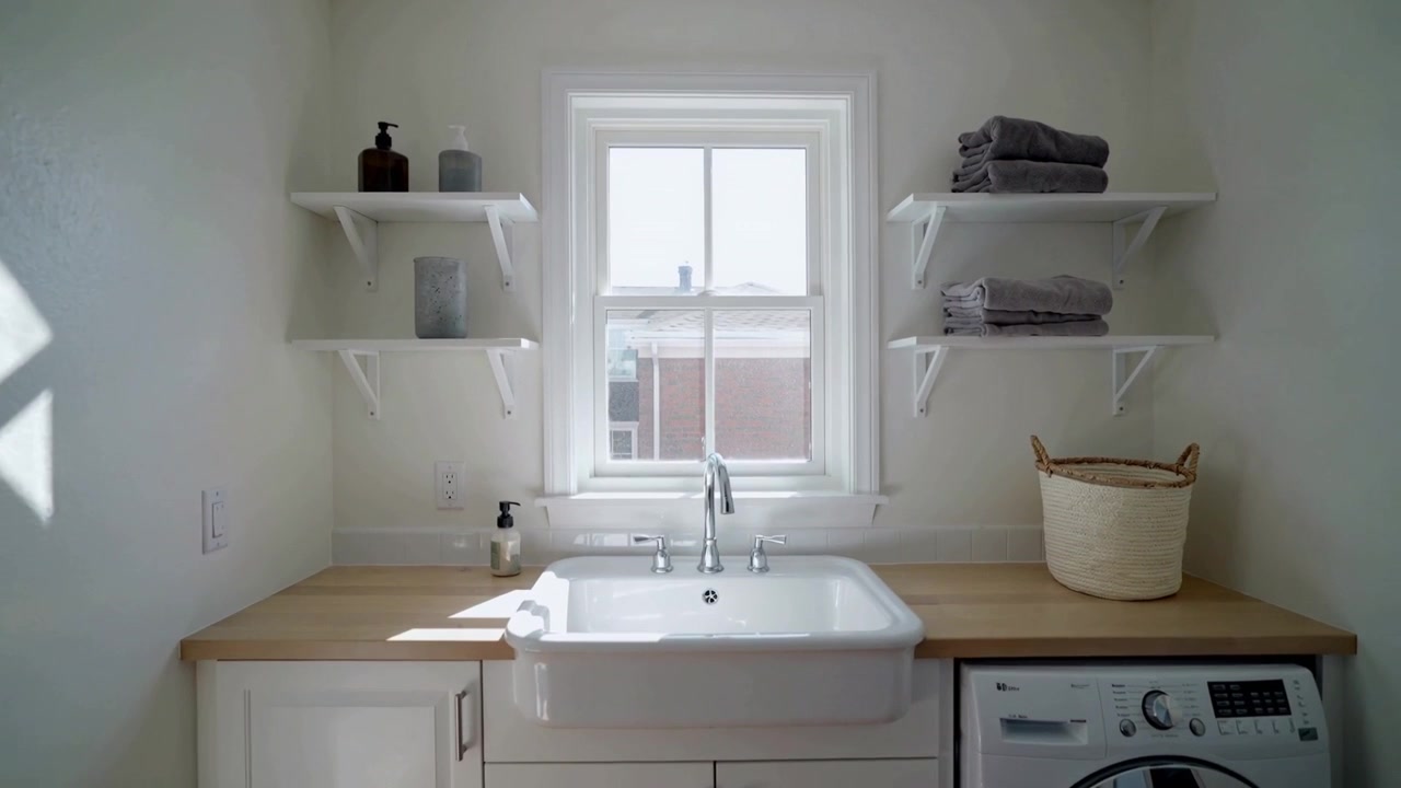 Sunlight shifting, camera zooming, farmhouse sink gaining focus in laundry room with basket, towels